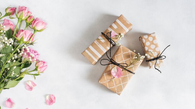 Rosas maravillosas frescas cerca de cajas de regalo y pétalos