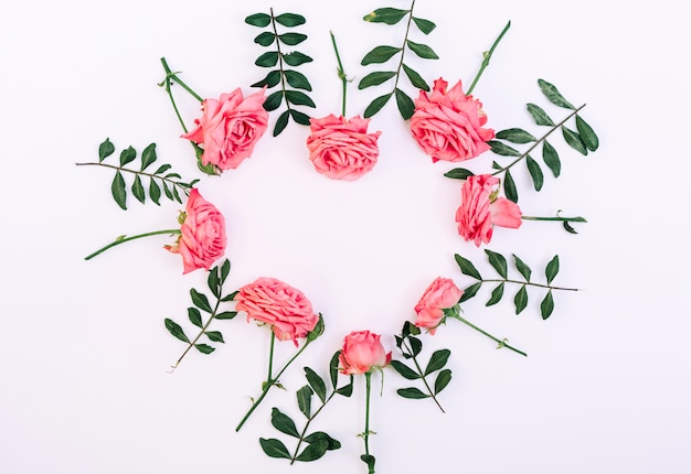 Rosas rosadas decorativas dispuestas en forma de corazón sobre fondo blanco