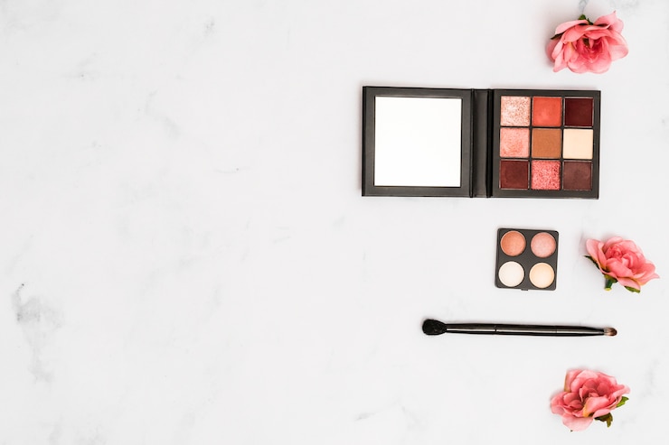 Foto gratuito rosas rosadas con pincel de maquillaje y paleta de sombras de ojos en el fondo