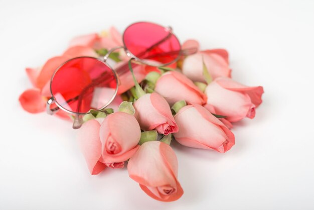 Rosas rosas con gafas de sol en mesa.