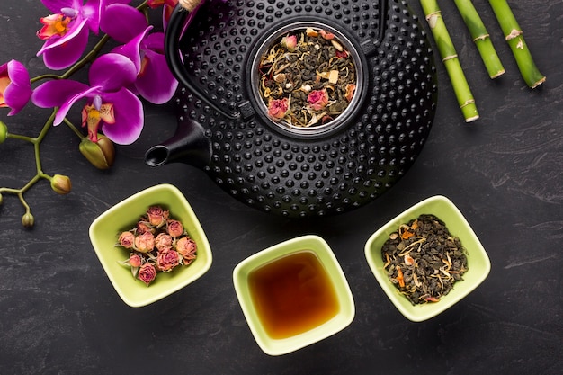 Rosas secas e ingrediente de té de hierbas con flor de orquídea sobre fondo negro