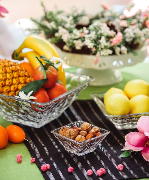 Roseta de vista lateral con nueces en la cáscara y un plato de frutas y limones sobre la mesa