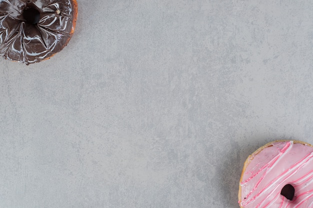 Foto gratuita rosquillas de chocolate y rosa sobre una superficie de hormigón