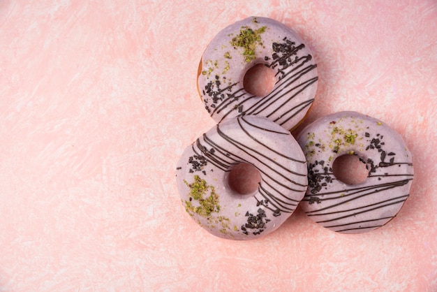 Rosquillas de fresa rosa aisladas sobre fondo rosa.