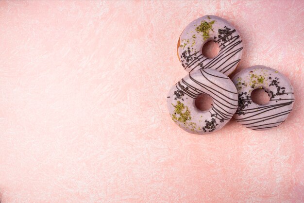 Rosquillas de fresa rosa aisladas sobre fondo rosa.