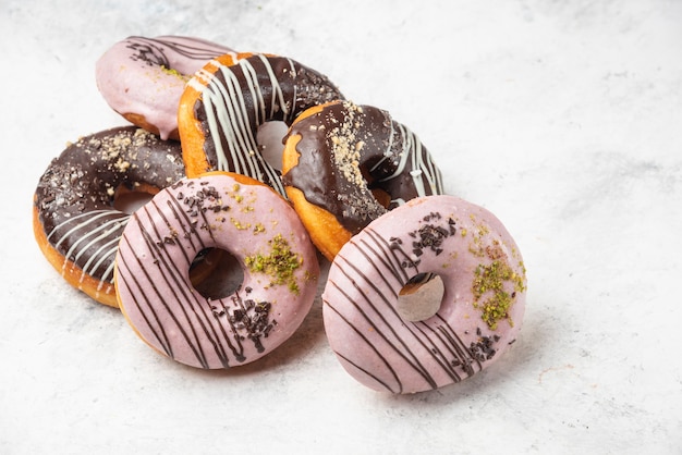 Rosquillas glaseadas de chocolate y rosa sobre superficie de mármol.