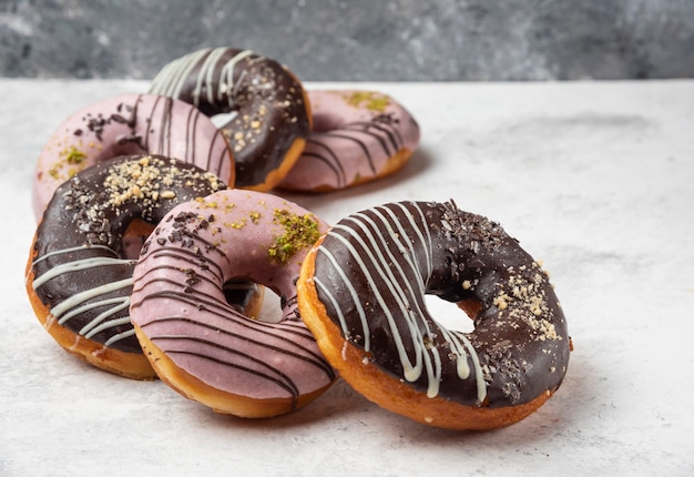 Rosquillas glaseadas de chocolate y rosa sobre superficie de mármol.