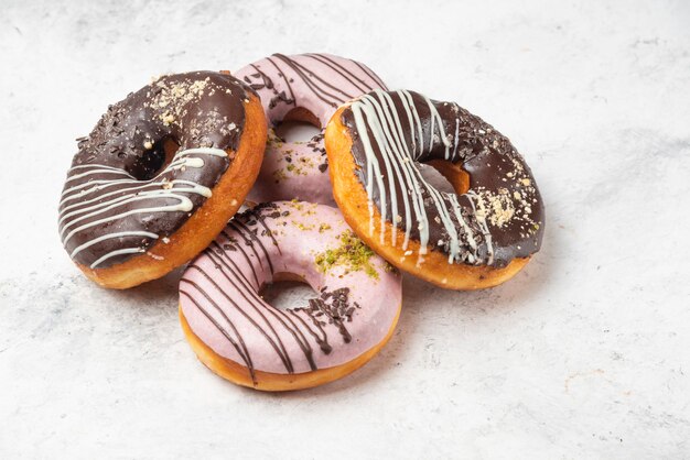 Rosquillas glaseadas de chocolate y rosa sobre superficie de mármol.