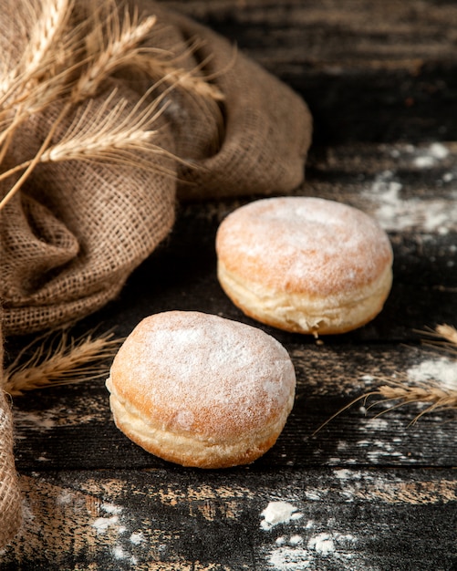 Foto gratuita rosquillas rellenas de crema con crema de mantequilla y azúcar en polvo sobre la mesa