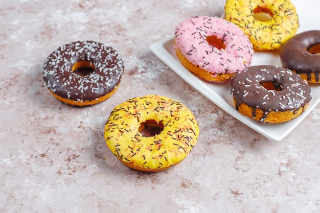 Rosquillas surtidas con glaseado de chocolate, glaseado rosa y chispitas.