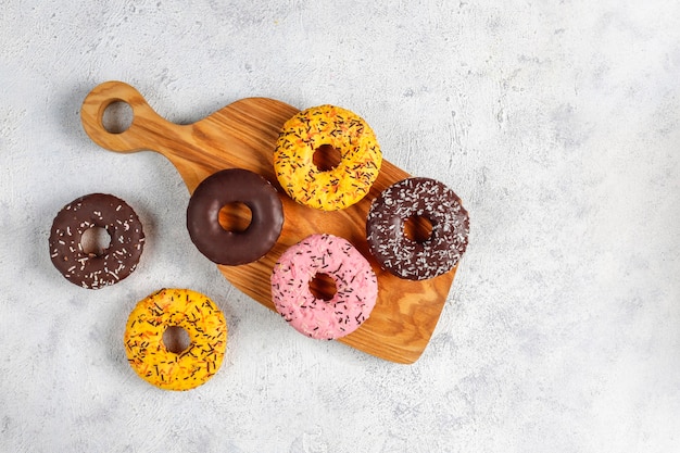 Rosquillas surtidas con glaseado de chocolate, glaseado rosa y chispitas.