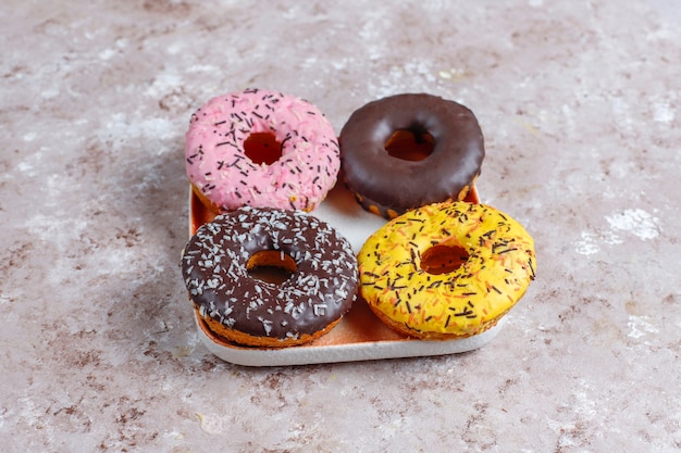 Rosquillas surtidas con glaseado de chocolate, glaseado rosa y chispitas.