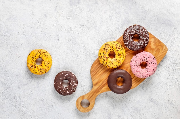 Rosquillas surtidas con glaseado de chocolate, glaseado rosa y chispitas.