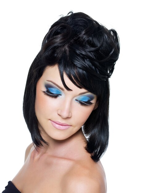 Rostro de una bella mujer joven con maquillaje azul brillante. Aislado en blanco