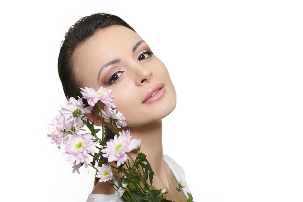 Rostro de belleza de la joven bella mujer con flores de colores aislados en blanco