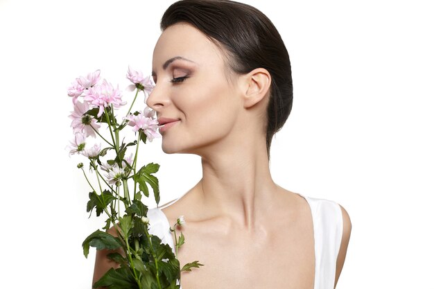 Rostro de belleza de la joven bella mujer con flores de colores aislados en blanco