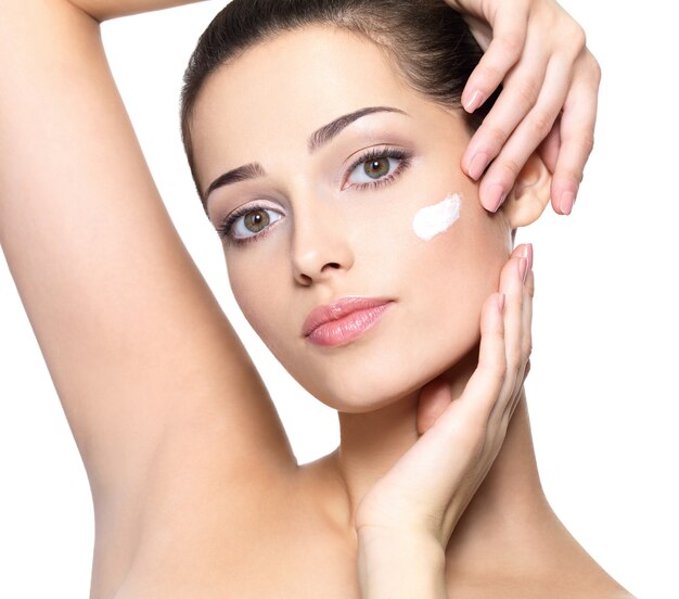Rostro de belleza de mujer joven con crema cosmética en la mejilla. Concepto de cuidado de la piel.
