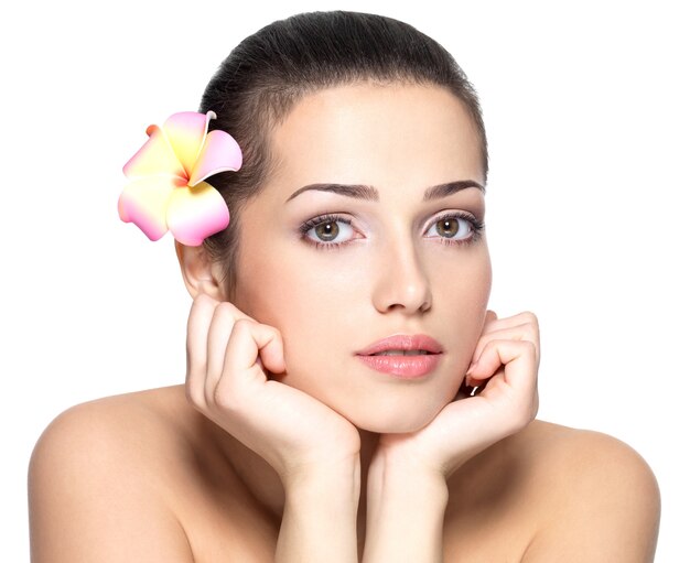 Rostro de belleza de mujer joven con flor.