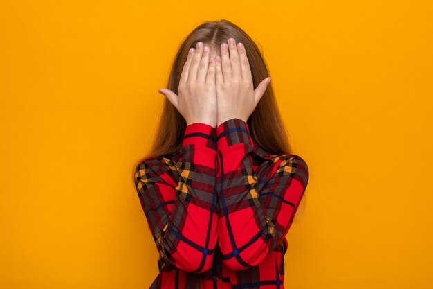 Rostro cubierto con las manos hermosa niña vestida con camisa roja