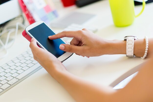 sin rostro femenino que usa smartphone sentado mesa