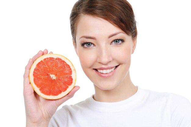 Rostro femenino sonriente con pomelo fresco en sus manos