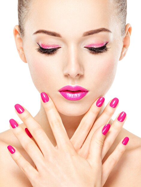 Rostro de mujer hermosa con maquillaje rosa de ojos y uñas. Retrato de modelo de moda glamour