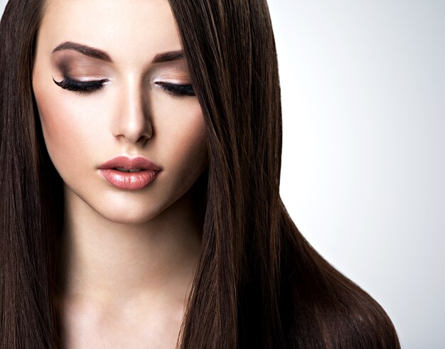 Rostro de mujer joven hermosa con maquillaje marrón y cabello lacio