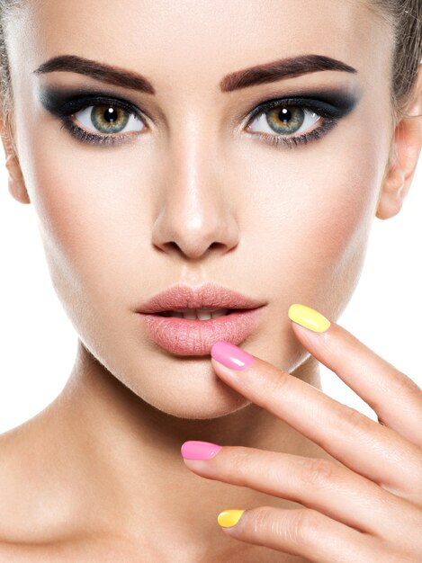 Rostro de mujer joven hermosa con uñas multicolores