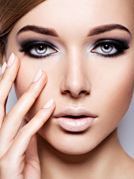 Rostro de mujer con maquillaje negro de moda de ojos y pestañas negras largas.