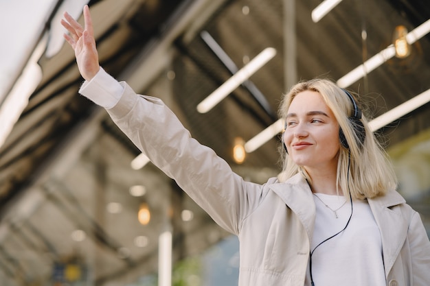 Rubia camina en la ciudad de verano con auriculares