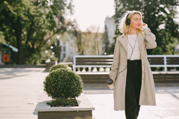 Rubia camina en la ciudad de verano con una taza de café