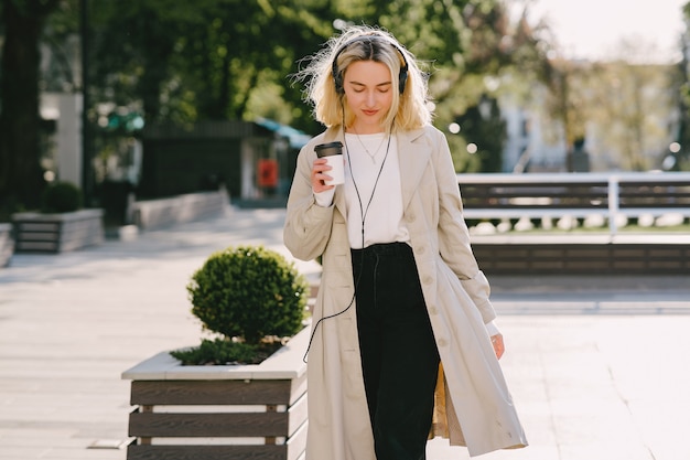 Rubia camina en la ciudad de verano con una taza de café