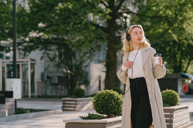 Rubia camina en la ciudad de verano con una taza de café