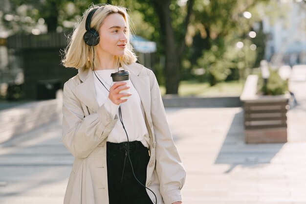 Rubia camina en la ciudad de verano con una taza de café