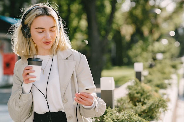 Rubia camina en la ciudad de verano con una taza de café