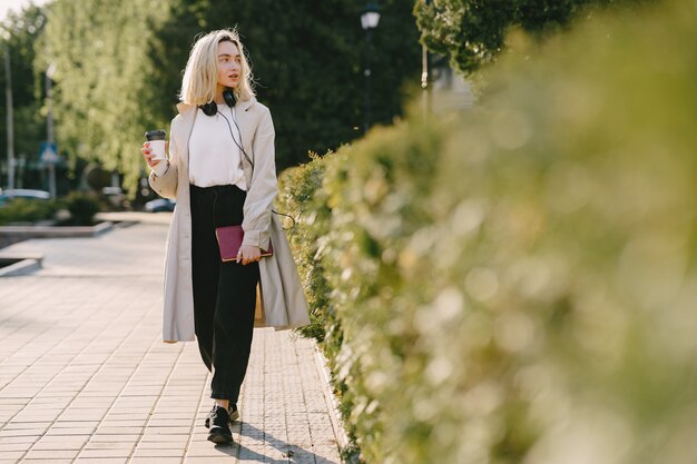 Rubia camina en la ciudad de verano con una taza de café