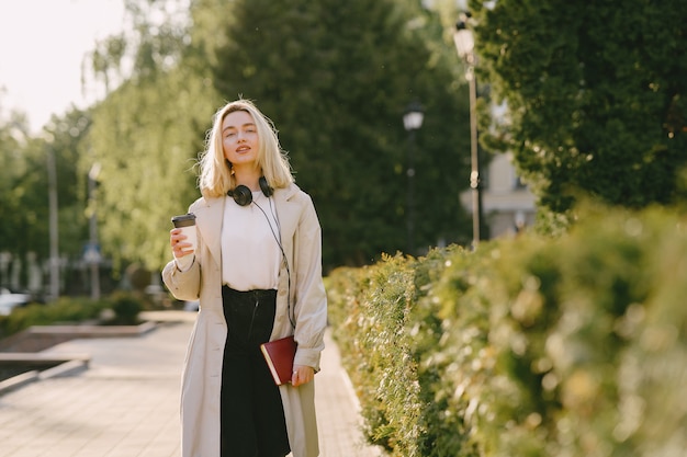 Rubia camina en la ciudad de verano con una taza de café