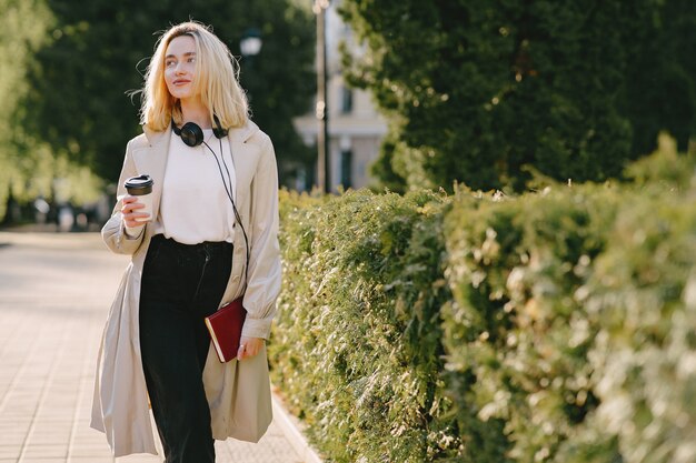 Rubia camina en la ciudad de verano con una taza de café