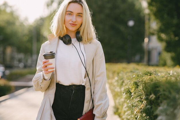 Rubia camina en la ciudad de verano con una taza de café