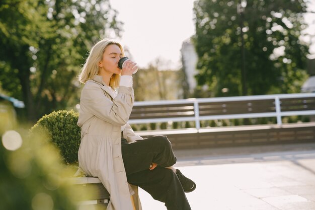 Rubia en una ciudad veraniega con una taza de café