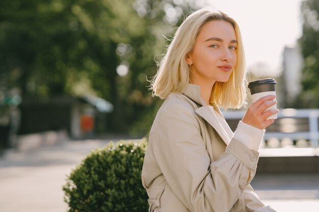 Rubia en una ciudad veraniega con una taza de café