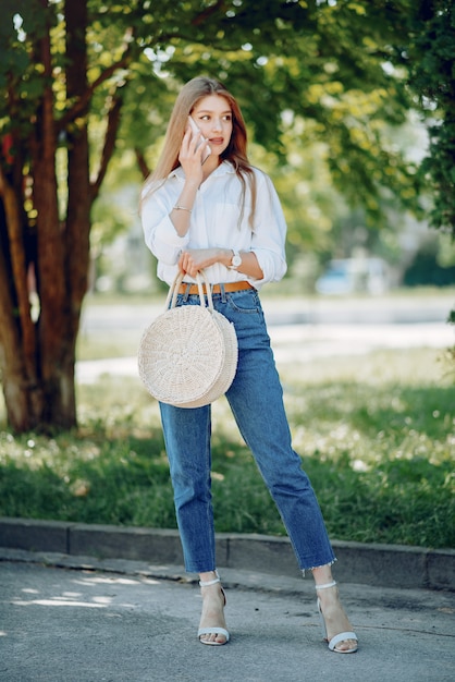 Rubia elegante en un parque de verano con teléfono