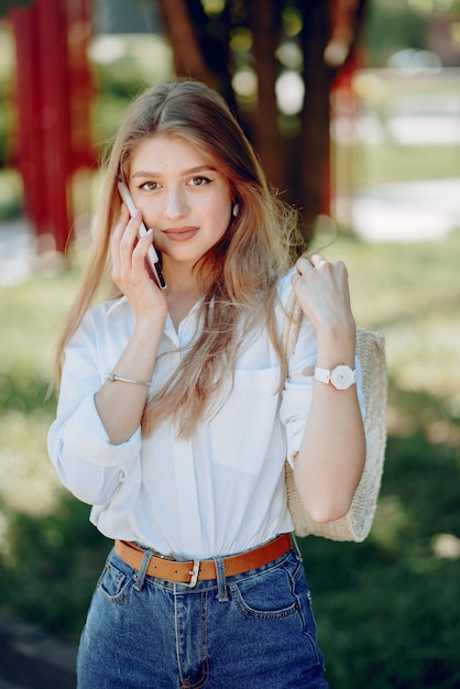 Rubia elegante en un parque de verano con teléfono