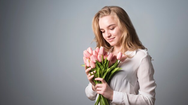 Rubia encantadora disfrutando de un ramo de flores