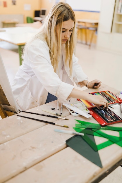 Rubia joven eligiendo lápiz de color de la caja