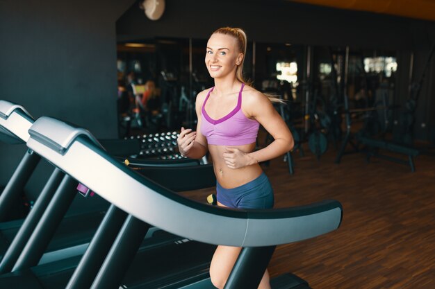 Rubia joven, motivada, mujer corriendo en la cinta