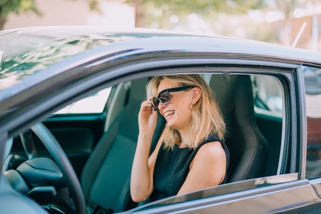 Rubia joven sentada en el coche riendo