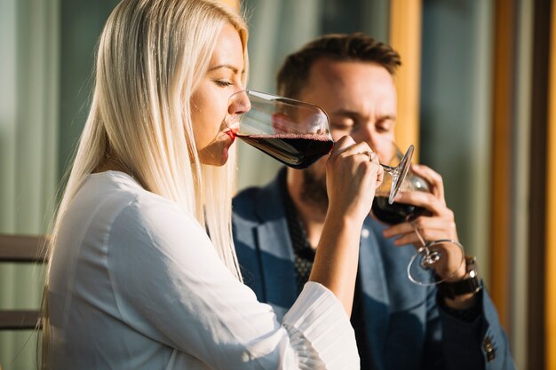 Rubia joven y su novio bebiendo copa de vino tinto