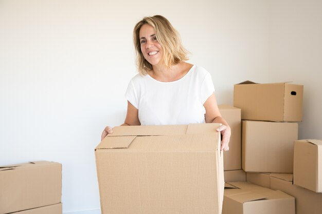 Rubia mujer caucásica con caja de cartón en casa nueva o apartamento