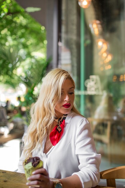 Rubia pelo largo con muffin de chocolate en la cafetería